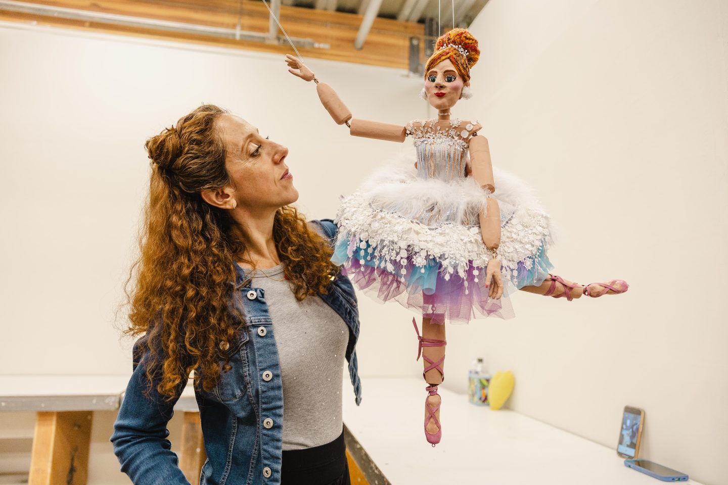 artist holding and examining a marionette figure in a sculpture studio at Anderson Ranch Arts Center