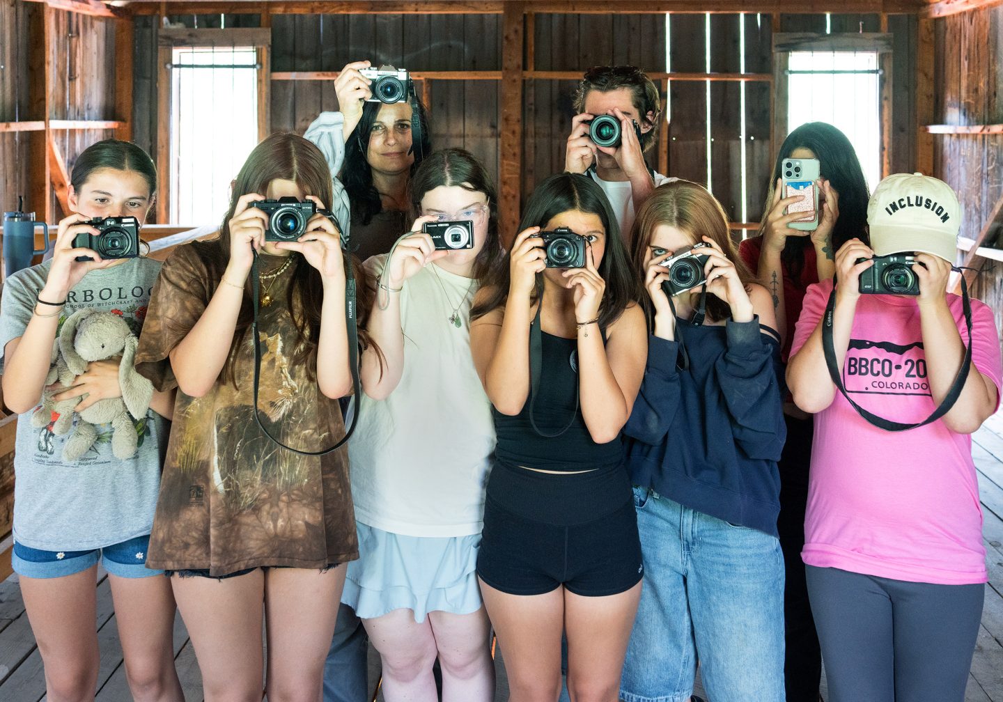 Group of teens and instructor holding cameras during a photography workshop.